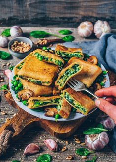 a person is holding a fork over some food on a plate with garlic and spinach