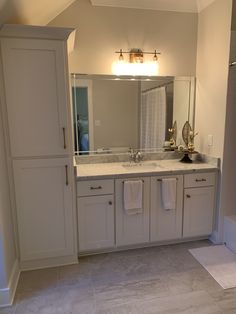 a bathroom with white cabinets and marble counter tops