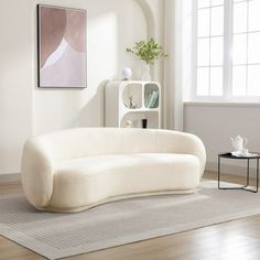 a living room with a white couch and coffee table on the floor in front of a window