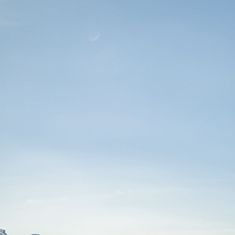 two people are flying kites in the sky on a clear day with mountains in the background