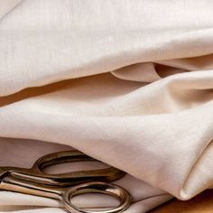 a pair of scissors sitting on top of a white cloth next to a wooden table