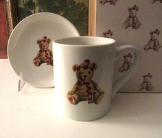 a white coffee cup with a teddy bear on it and another mug next to it