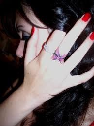 a woman with long black hair and red nails holding her hand up to her face