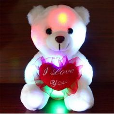 a light up teddy bear holding a heart with the words i love you on it