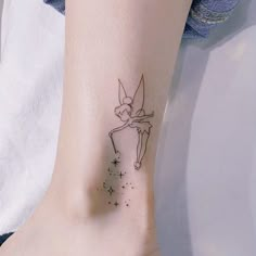 a small tattoo on the ankle of a woman's foot with tinkerbell