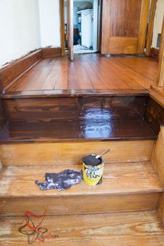 an empty wooden staircase with paint can and brush on the floor in front of it