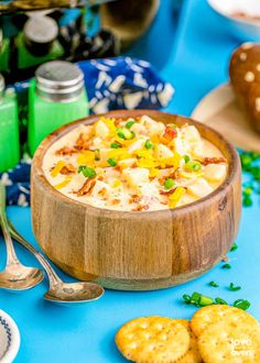 a wooden bowl filled with food sitting on top of a blue table next to crackers