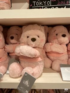 several pink teddy bears are sitting on a shelf in a store with tags around them