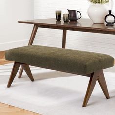 a wooden bench sitting next to a table on top of a white rug