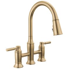 a kitchen faucet with two handles and nozzles on the side, in gold