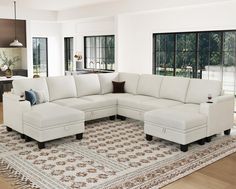 a white sectional couch sitting on top of a rug in a living room next to a window