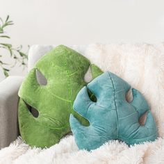 two pillows sitting on top of a white couch next to a potted green plant