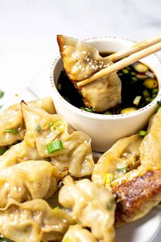 some dumplings are on a plate with chopsticks