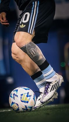 a soccer player with tattoos on his legs kicking a soccer ball in front of him