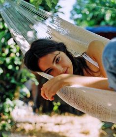 a beautiful woman laying in a hammock with her hand on the back of it