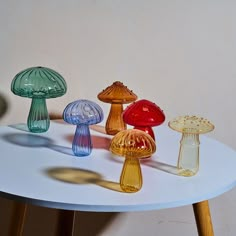 several different colored glass mushrooms on a white table