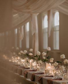 a long table with white flowers and candles in vases on top of each table