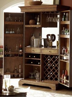 a wooden cabinet filled with lots of bottles and glasses on top of it's shelves