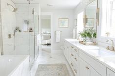 a white bathroom with two sinks and a bathtub next to a large mirror on the wall