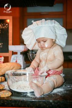 a baby is sitting on the counter in front of a mixing bowl with flour inside