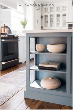 a book shelf in the middle of a kitchen with bowls and books on it's shelves