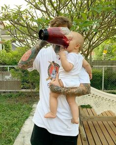 a man is holding a baby and drinking from a bottle