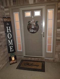 a welcome sign is on the front door of a home with a welcome mat in front of it