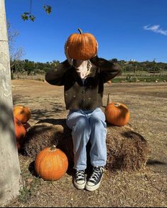 a person sitting on top of a hay bale with pumpkins