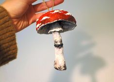 a hand holding a red and white mushroom ornament