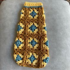 a crocheted oven mitt with blue and yellow flowers on the side sitting on a table