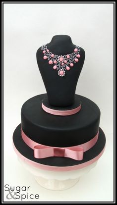 a black and pink cake with a necklace on top