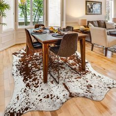 a dining room table with chairs and a cowhide rug