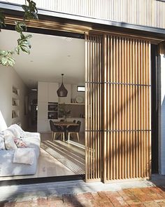 an open sliding glass door leading to a living room and dining area with brick flooring