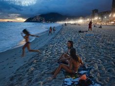 people are sitting on the beach at night