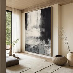 a large abstract painting hangs in the corner of a living room with two vases