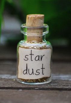 a small bottle filled with star dust sitting on top of a wooden table