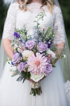 a bride holding a bouquet of purple and white flowers