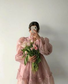 a woman taking a selfie with her cell phone while holding a bouquet of flowers