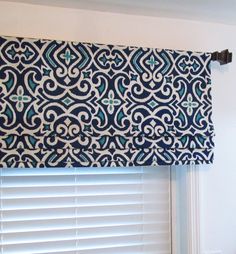 a blue and white patterned window valance hanging on the side of a window sill