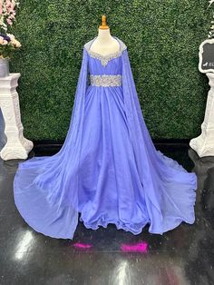 The Samantha Blake 1023 Girls Long Cape Sleeve Pageant Dress is perfect for any special occasion. The crystal cut out back and A line silhouette add a touch of elegance to the chiffon material. With long cape sleeves flowing from a cap sleeve, your child will feel like a true princess in this beautiful dress. Perfect Unique look for Pageants! Sizes: 2-16 Colors: Periwinkle Pageant Dresses With Capes, Embellished Organza Pageant Dress, Elegant Dresses With Sweep Train For Pageant, Elegant Sweep Train Dress For Pageants, Elegant Sweep Train Dress For Pageant, Elegant Chiffon Dress For Dress-up Occasions, Blue Gown With Cape Sleeves For Party, Luxury Blue Dress With Cape Sleeves, Blue Fitted Maxi Dress With Cape Sleeves