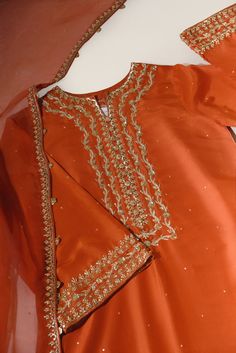 A beautiful festive look in the captivating shade of burnt orange, crafted on pure raw silk in a long kameez silhouette, heavily embellished with gold zardozi craftsmanship, each stitch is a testament to generations of artistry. Completing this masterpiece of a design is a fully embellished soft pure organza dupatta, a Burnt Orange Pakistani Outfit, Long Kameez, Punjabi Suits Party Wear, Simple Suit, Suits Party Wear, Embroidery Fashion Detail, Zardozi Embroidery, Orange Outfit, Pakistani Fancy Dresses