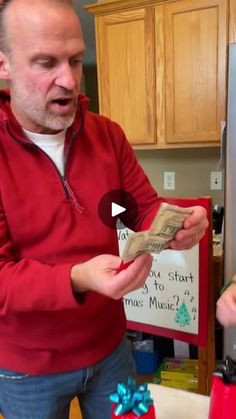 a man holding money in his hands while standing next to another man with a christmas present