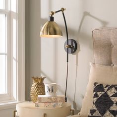 a lamp on the wall next to some pillows and a table with a coffee cup