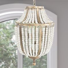 a chandelier with beads hanging from it's sides in front of a window