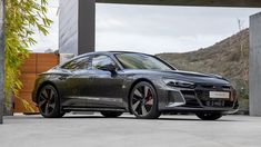 a grey car parked in front of a building with mountains in the backgroud