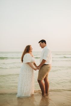 young newly engaged couple wearing white & beige hold hands, facing each other while standing barefoot on the edge of the water St. Andrews State park, PCB Florida.  Portrait captured by Brittney Stanley of Be Seen Photos Goa Beach Couple Photos, Panama City Beach Picture Ideas, Old Panama City Beach Florida, Wrightsville Beach Engagement Photos