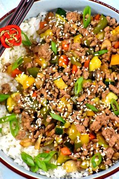 a bowl filled with rice, meat and veggies next to chopsticks