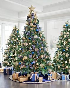 a christmas tree with blue and gold ornaments is shown in the middle of a room