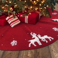 a christmas tree with presents under it on a red rug next to a christmas tree