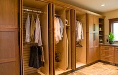 an organized closet with clothes hanging on the wall and doors open to let in plenty of light